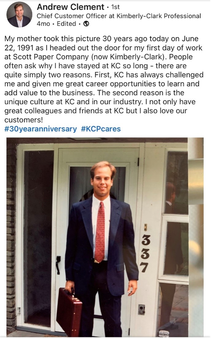 Social Media Screenshot of Andrew as he stands in front of his front door holding a briefcase and wearing a suit with a red tie.